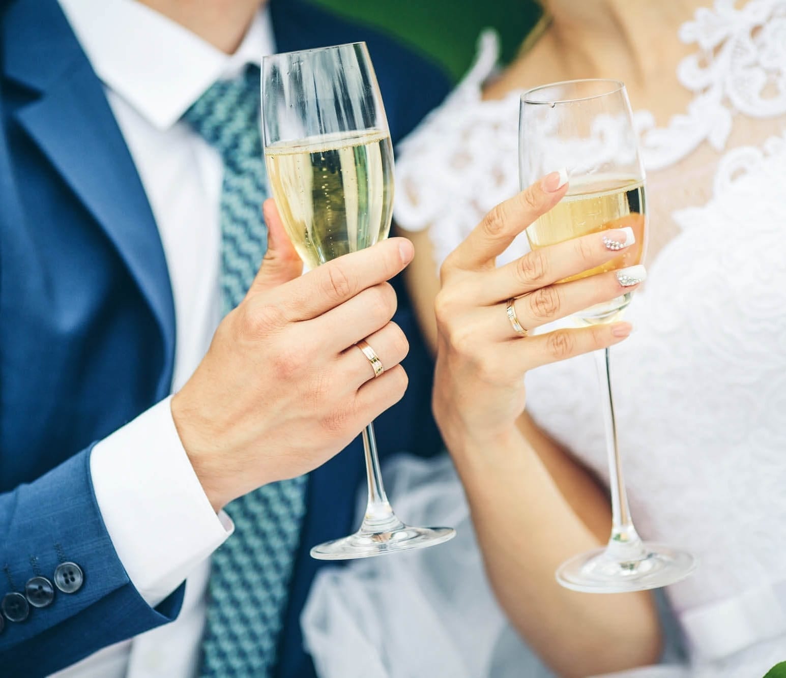 Close-up of wedding couple holding champagne glasses.
