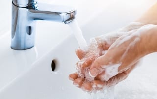 Photo of a Woman Washing Her Hands. Click Here for Tips For Staying Healthy While Traveling.